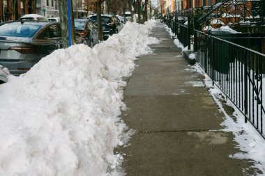 Hoboken, NJ 'de bir kaldırım kışın yakınlarda park edilmiş arabalarla karla kaplı..