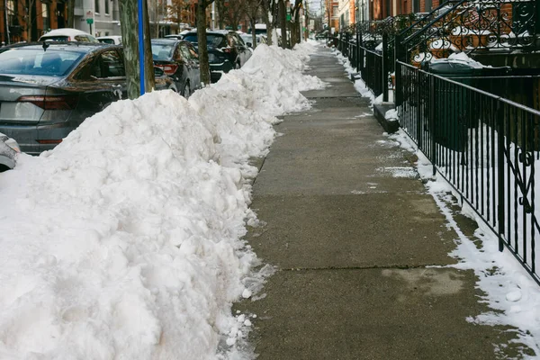 Hoboken, NJ 'de bir kaldırım kışın yakınlarda park edilmiş arabalarla karla kaplı..