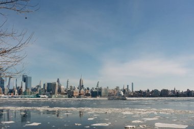 New York 'un siluetinde mavi gökyüzünün altında bir kış günü boyunca buzla kaplı yüksek binalar yer alır.
