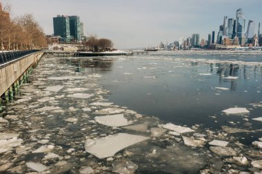 Buz kütleleri şehrin yakınındaki nehirde yüzer ve kış boyunca arka planda binalar görülebilir..