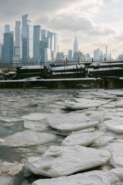 New York City 'deki binalar kış boyunca bulutlu bir gökyüzüne karşı dimdik dururken, buzlar suda şekilleniyor..