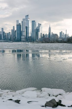 New York şehrinin ufuk çizgisi, öğleden sonraları bir kış sahnesinde yüksek binalar ve buzlar gösteriyor..
