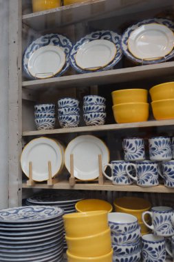 Gündüzleri işlek bir markette raflarda çeşitli tabak ve bardaklar parlak renklerde sergilenir..