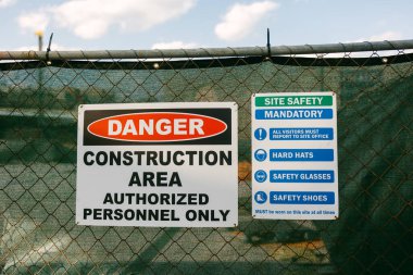 Bir tabelada, gün içinde kentsel bir yerin yakınında güvenlik gereklilikleri uyarısı bulunan bir inşaat alanı olduğu belirtiliyor..