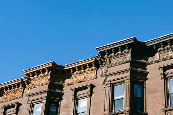 Tarihi bir binanın çatısı, yoğun bir kentsel alanda açık bir gökyüzüne karşı gün boyunca karmaşık planlar gösteriyor..
