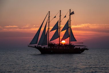 Yunanistan 'da günbatımında akşam gökyüzünün arka planında güzel bir yelkenli.