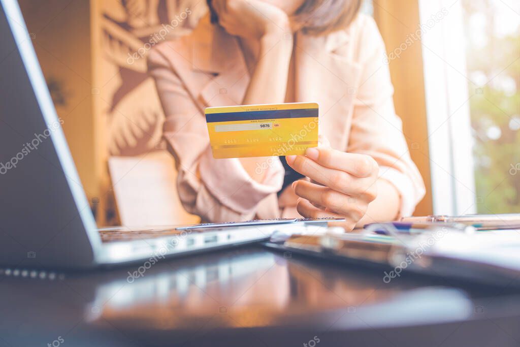 Business people holding credit cards and using laptops shopping online.