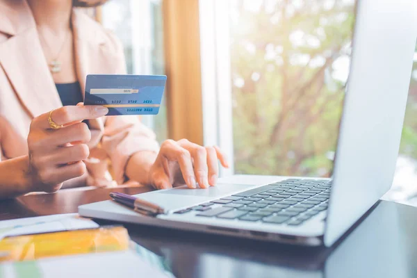 Kredi kartı tutan ve dizüstü bilgisayar kullanan iş adamları internetten alışveriş yapıyor..