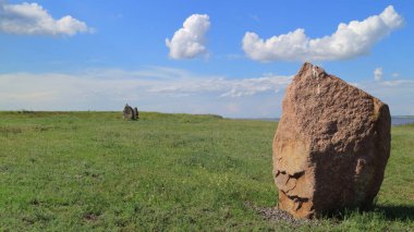 Açık bozkırda yeşil çimlerin üzerinde duran büyük kayalar..