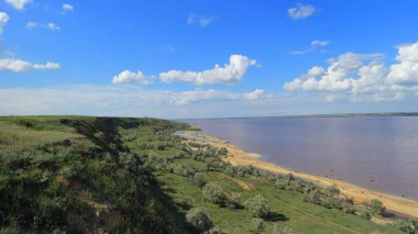 Mavi gökyüzü, beyaz bulutlar ve pembe su ile sarp bir uçurumdan gölün güzel manzarası çiçek açan mikroorganizmalar tarafından yaratılmıştır..