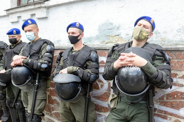 KYIV, UKRAINE - 21 Mayıs 2021: Askeri polis, polisin yetkisini kötüye kullanmasına karşı düzenlenen protesto eyleminde miğfer tutuyor. Protestocular yaratıcı gençlik safarisine bir son verilmesini talep ediyorlar.