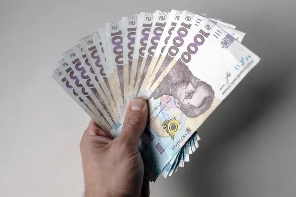 Erkek eli birkaç bin Hryvnia tutuyor. Beyaz bir arka planı olan Ukrayna para birimi. Bin tane Hryvnia düzinesi banknot. Ukrayna parası. Banknotlar