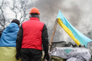 KYIV, UKRAINE - 28 Ocak 2014: Sokak barikatlarındaki insanların sırtları. Özgürlük mücadelesi sırasında Ukrayna bayrağı