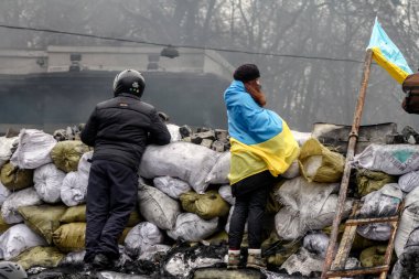 KYIV, UKRAINE - Jan 28 2014: A girl wrapped in a Ukrainian flag stands against the backdrop of barricades during the Revolution of Dignity, struggle for freedom clipart