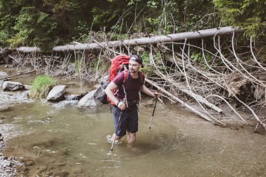 Bir yürüyüşçü nehirde dizlerinin üstünde, dağlarda, Chyvchyny 'de, Karpatlar' da Ukrayna-Romanya sınırında yürüyor.