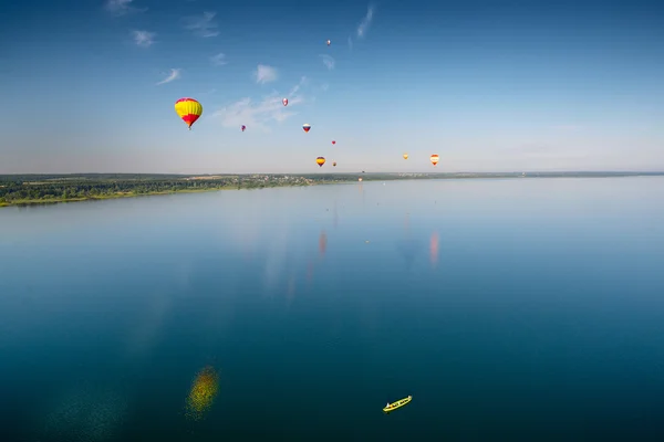 Hot air balloons flying over lake. — Stock Photo, Image