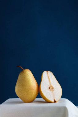 Mavi arkaplana karşı beyaz bir masada sarı taze armut, metin için yeri olan minimalist resim