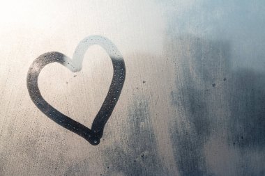 El, donmuş pencereye doğal güneş ışığı ile kalp çiziyor