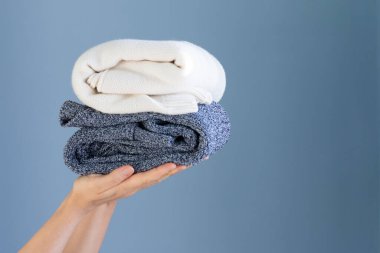 Eller mavi arkaplan üzerinde süveter tutarken metin için boş alan