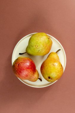 Kahverengi zemine karşı beyaz tabakta iki armut, üst manzara