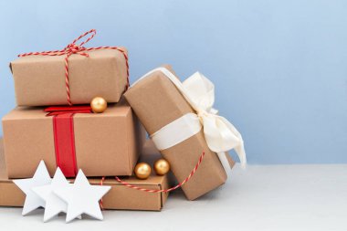 Kağıtlardan el yapımı hediye kutusu ve açık mavi arka planda izole edilmiş kurdele.