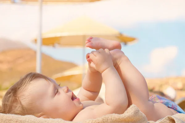 Szczęśliwe dziecko opalając się na plaży solarium. — Zdjęcie stockowe