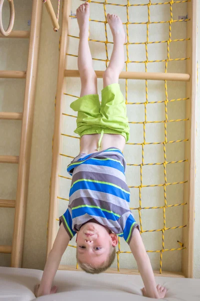 Child stands upside down in gym — Stock Photo, Image