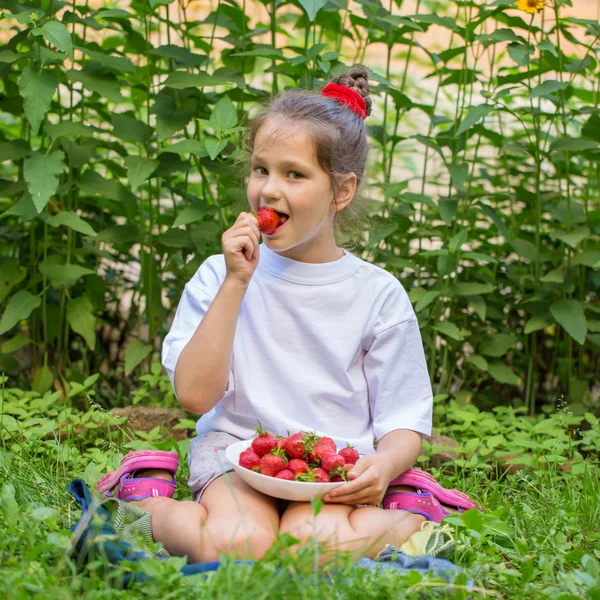 Barn i vit T-shirt äta jordgubbar — Stockfoto