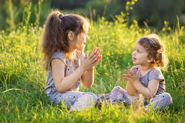 Dwoje dzieci, rozmowy i zabawy na trawie. — Zdjęcie stockowe