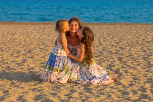 Crianças beijando e abraçando a mãe na praia . — Fotografia de Stock