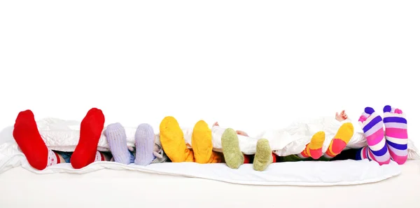 Familia feliz en calcetines de colores en la cama blanca . Fotos De Stock