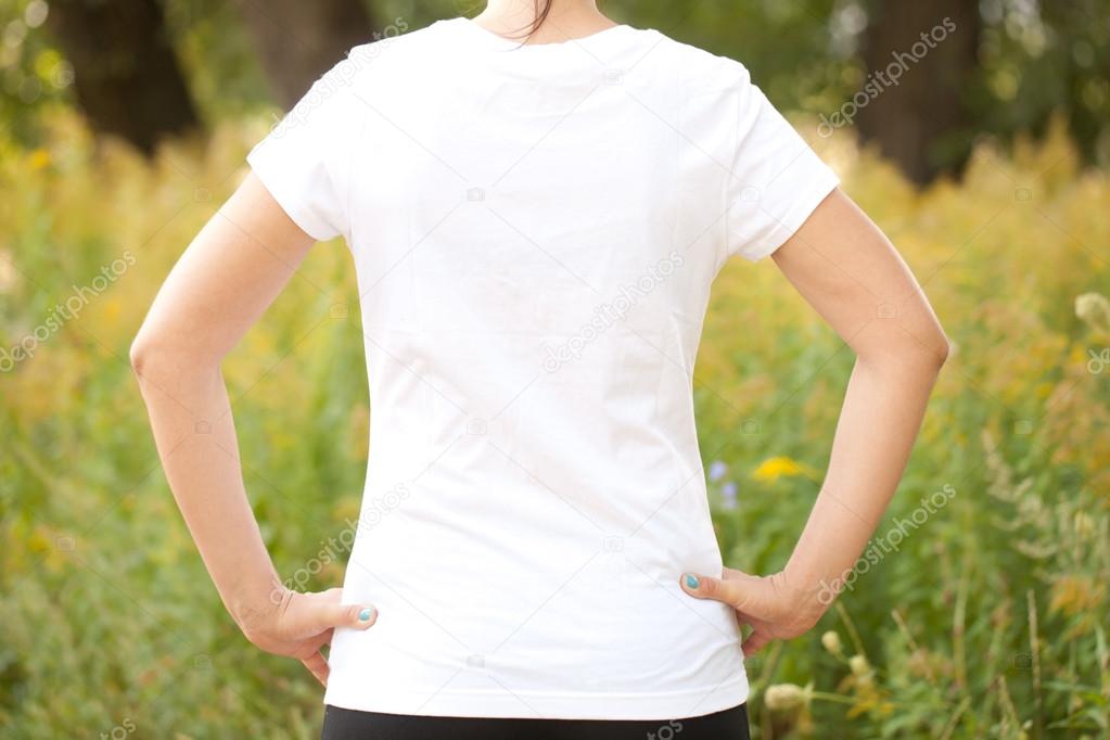 Young woman in white t-shirt outdoors. Ready for your text, logo or symbol. Rear view.