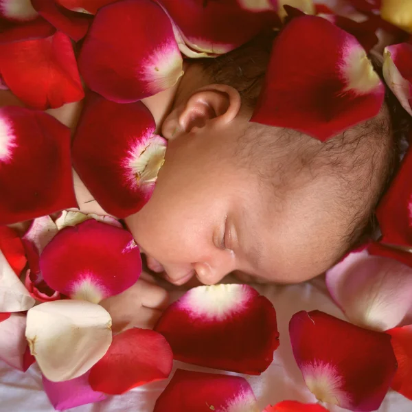 Black baby sleeping in rose petals — Stock Photo, Image