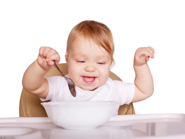 Engraçado bebê comendo com colher em cadeira alta — Fotografia de Stock