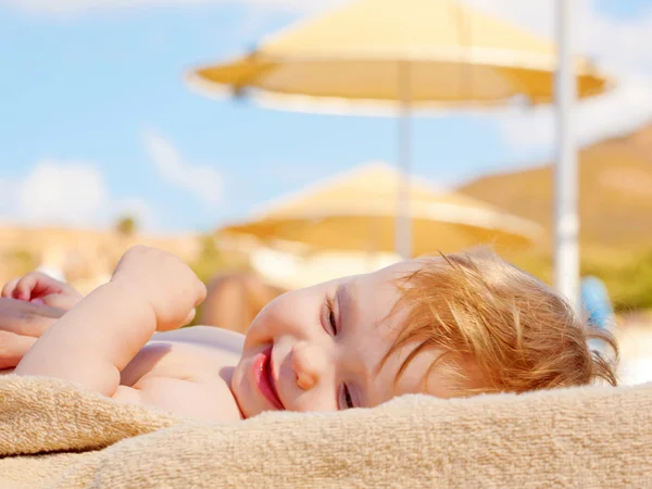 Glückliches Baby auf der Sonnenliege am Strand. — Stockfoto