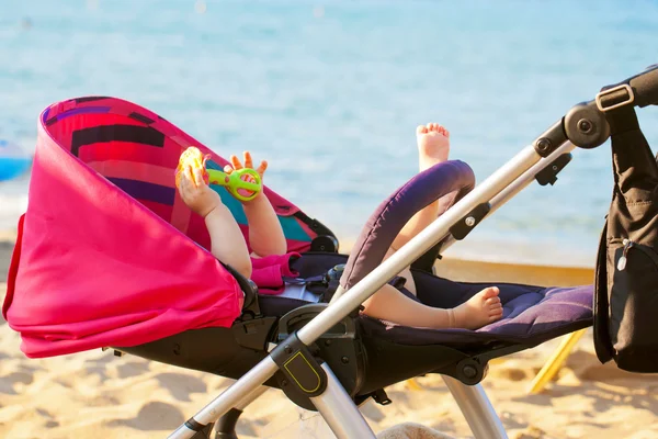 Baby liegt im Kinderwagen am Strand — Stockfoto