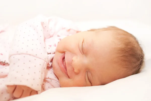 Smiling newborn baby sleeping on white — 图库照片
