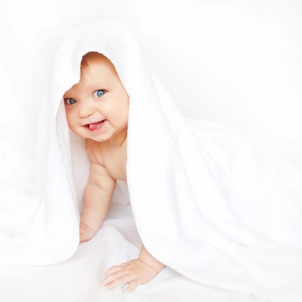 Bebê sob a toalha mostrando língua . — Fotografia de Stock