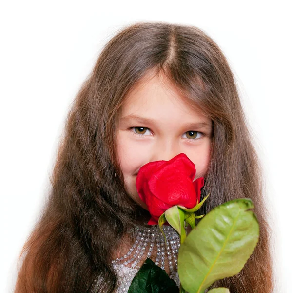 Kleines Mädchen, das eine rote Rose riecht. — Stockfoto