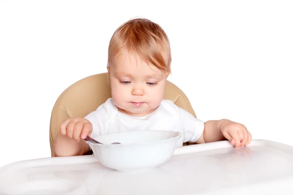 Baby eating with spoon in high chair — Stock Photo, Image