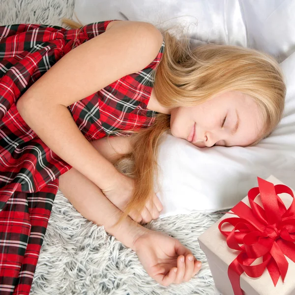 Kleines Mädchen, das mit Geschenk schläft. Träume werden wahr! — Stockfoto