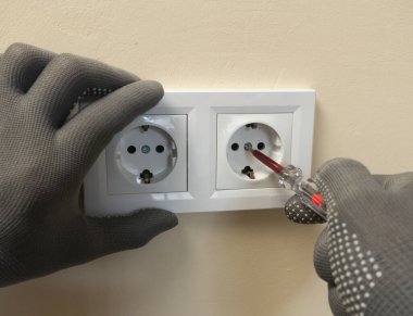 Elektrikçi prizi tamir eder, vidayı prize sokar, duvara sabitler..