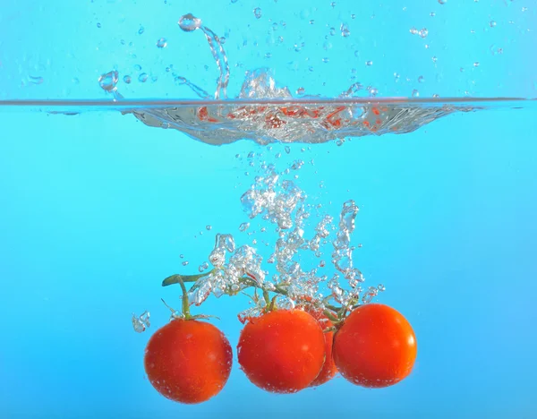 Red tomatoes dropped into water — Stock Photo, Image