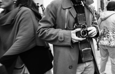 Şehirdeki insanların fotoğraflarını çeken hippi bir adam, sokak gösterileri sırasında kalabalığın içinde fotoğraf çeken ünlü bir retro kamerayla fotoğrafçı, sokak fotoğrafçılığı tarzı, B & W