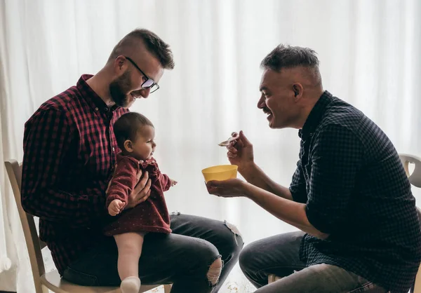 Evlatlık kızı olan erkek eşcinsel çift - iki yakışıklı baba mutfakta bebeğe bakıyor - erkek bakıcılar - Lgbt ailesi evde - çeşitlilik kavramı