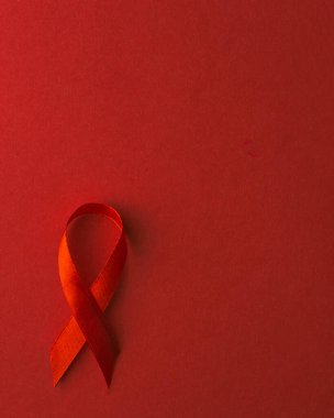 Kırmızı kurdele sembolü HIV, AIDS kanseri gölgeli farkındalık, kırmızı arka planda izole edilmiş stüdyo çekimi, sağlık sigortası konsepti, Dünya AIDS Günü
