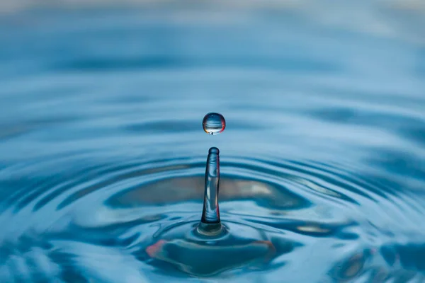 Blå vatten droppe stänk med röda toner — Stockfoto