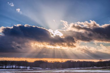 Güneş ışığıyla karlı tarlanın üzerinde gün batımı