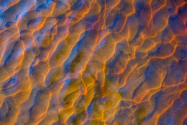 Altında kum dalgaları olan temiz altın su akıntısı deseni