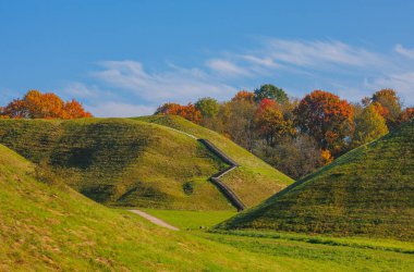 Renkli yaprakların sergilendiği, üzerinde güzel, sakin bir gökyüzü bulunan, gerçekten resimli bir sonbahar sahnesi. Kernave, Litvanya.